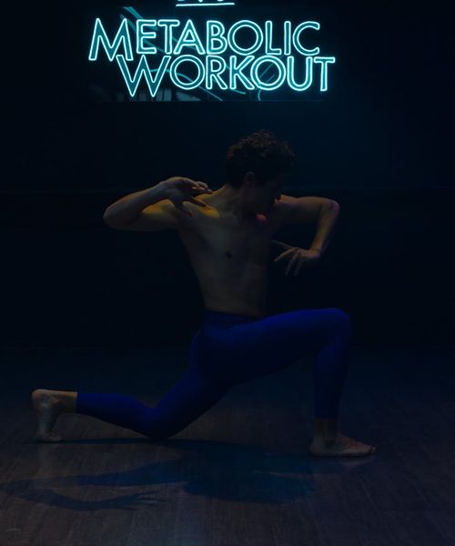Man performing a strength exercise in a modern, dark fitness studio.